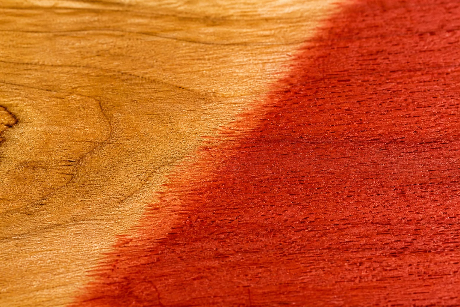 Macro view of ribbon-red color meeting the warm surface of a gallery panel.